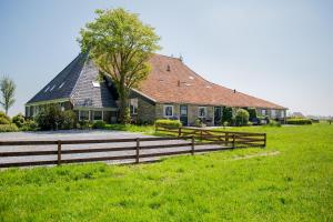 Boerderij Appartementen Ûnder de Wol - Súdwest Fryslân في Oudega: منزل أمامه سور خشبي