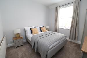 um quarto branco com uma cama com almofadas e uma janela em The Hideaway - IH113AHIG em Stockton-on-Tees