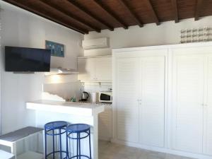 a kitchen with white cabinets and two blue bar stools at Petit Andromeda Mykonos I in Mikonos