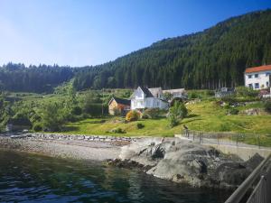 a group of houses on a hill next to the water at Feriehus med badestamp in Lavik