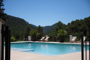 a swimming pool with chairs and mountains in the background at Apartamentos Cortijo Peñardera in Siles
