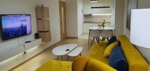 a living room with a yellow couch and a tv at Lux Apartment Flatiron Skopje in Skopje
