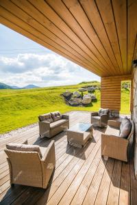 una terraza de madera con sofás, mesa y sillas en Apartmány Tatry Žiarce, en Liptovský Mikuláš