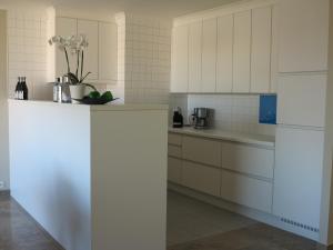 una cocina con armarios blancos y electrodomésticos blancos en Penthouse SPARTA, en Koksijde