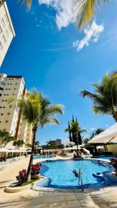 - une piscine avec des palmiers dans un complexe dans l'établissement Flat Prive das Thermas II - R3 Caldas, à Caldas Novas