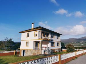 a white house with a balcony on top of a fence at Casa Courcelles - Viveiro in Viveiro