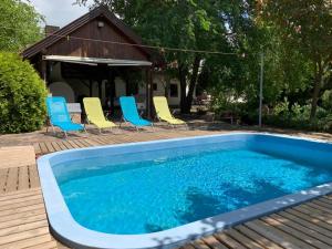 una piscina con sillas azules y amarillas y una casa en Bivaly Tanya en Domaszék
