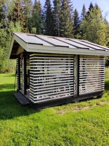 a wooden shed with a solar roof on a field at Haaran torppa in Mikkeli