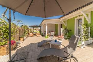 a patio with chairs and an umbrella at SMARTFIT HOUSE - Room & Relax in Pescara