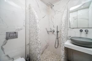 ein weißes Bad mit einem Waschbecken und einer Dusche in der Unterkunft Emmanouela Studios & Villas in Karterados