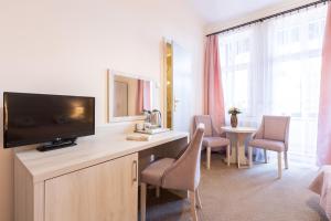a hotel room with a television and a table with chairs at Villa Elizabeth in Kudowa-Zdrój