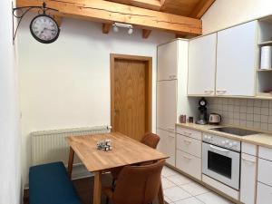 a kitchen with a wooden table and a clock on the wall at Kuschelige Ferienwohnung mit Balkon & Free Wifi in Buchenberg