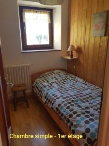1 dormitorio con cama con edredón y ventana en Gîte de la snaille en Le Reposoir