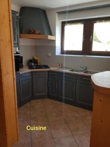 een keuken met blauwe kasten, een wastafel en 2 ramen bij Gîte de la snaille in Le Reposoir
