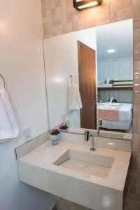 a bathroom with a sink with a mirror and a bed at Pousada Helena in Penha