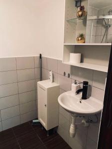 a white bathroom with a sink and a cabinet at Apartmánek Patricie room with kitchenette suitable for 2 adults and 2 children in Mikulov
