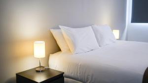 a bed with white pillows and a lamp on a table at São Pedro Apartment in Vila Franca do Campo