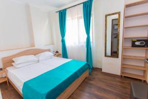 a bedroom with a bed with blue curtains and a mirror at Sorriso Mamaia Nord in Mamaia Sat/Năvodari