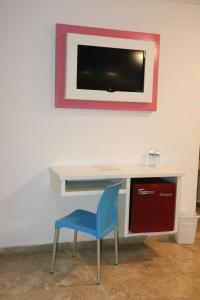 a desk with a blue chair and a tv on a wall at Miami Inn in Nuevo Vallarta