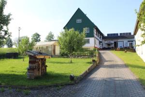 a house with a green roof and a brick driveway at Ferienwohnung am Kugelbaum in Lunzenau