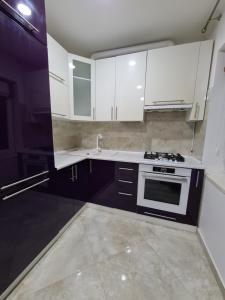 kuchnia z białymi szafkami i kuchenką w obiekcie 127-Avenue Apartment w Czerniowcach