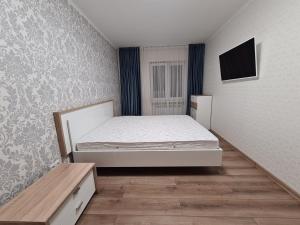 - une chambre avec un lit et une télévision murale dans l'établissement 127-Avenue Apartment, à Tchernivtsi