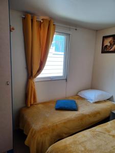 - une chambre avec 2 lits et une fenêtre dans l'établissement Flo's Mobil-Home, à Saillagouse