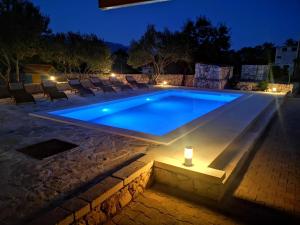 una piscina por la noche con una vela al lado en Apartman Magas with private pool, en Vinjerac