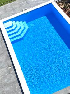 a blue swimming pool with a chair in the water at Balkon Apartmanház Panzió in Balatonfüred