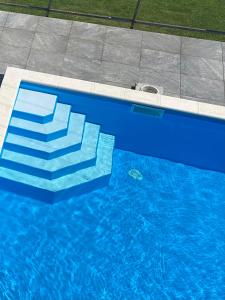 a blue swimming pool with stairs in the water at Balkon Apartmanház Panzió in Balatonfüred