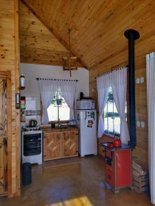 a kitchen with a stove and a refrigerator at Chalés Estância Cachoeira do Avencal in Urubici