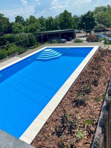 a blue swimming pool with a stone walkway around it at Balkon Apartmanház Panzió in Balatonfüred