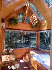 a large bathroom with a tub in a wooden house at Chalés Estância Cachoeira do Avencal in Urubici