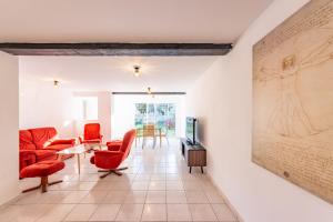 a living room with red chairs and a painting on the wall at Maison des bains - 3 chambres - Jardin - Wifi in Valence-dʼAgen