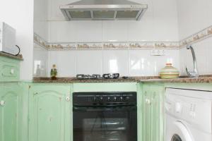 a kitchen with green cabinets and a black oven at Casa Parpatana in Conil de la Frontera