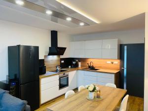 uma cozinha com uma mesa de madeira e um frigorífico preto em Apartmány DOME em Doksy