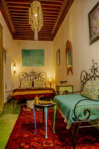 1 dormitorio con 2 camas, mesa y lámpara de araña en Riad Zarka en Marrakech