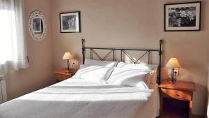 una camera da letto con letto, lenzuola e cuscini bianchi di Casa Rural Graner a Sant Llorenç de Morunys