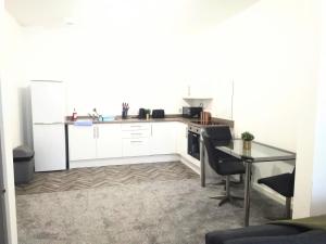 a kitchen with white cabinets and a glass table at Sigma Central Apartment 3 in North Shields