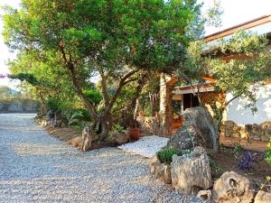 um jardim com pedras e uma árvore e uma casa em Il Ginepro em Villaputzu