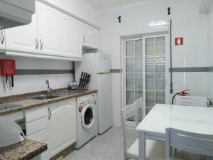cocina blanca con lavadora y mesa en Lili's Albufeira Apartment, en Albufeira