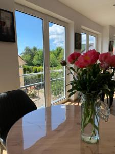 un vase de fleurs roses assis sur une table dans l'établissement HGH - Hotel Garni Helbig, à Neustadt an der Weinstraße