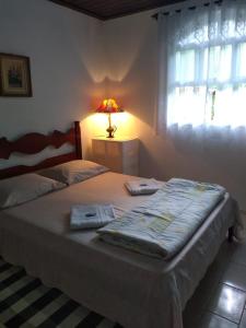 a bedroom with a bed with a lamp and a window at Chalé da Paz in Penedo