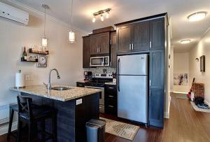 a kitchen with a stainless steel refrigerator and wooden cabinets at Le Champlain Condo-Hôtel in Bromont