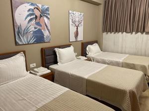 シュコダルにあるBobi Hotelのベッド3台が備わる客室で、壁には絵画が飾られています。