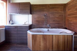 a bathroom with a tub and a kitchen with wooden walls at Napfenyes Vendeghaz in Bükkösd
