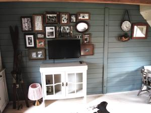 a living room with a tv and a wall with clocks at Chalet Lily in Žabljak