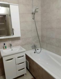 uma casa de banho com um lavatório, uma banheira e um chuveiro em Квартира в новобудові em Lutsk