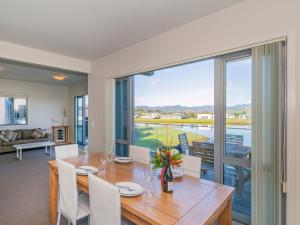 a dining room with a table and chairs and a large window at Matarangi Villa on Golf Course - Matarangi Home in Matarangi