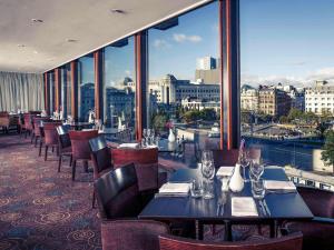 a restaurant with tables and chairs and a view of the city at Mercure Manchester Piccadilly Hotel in Manchester